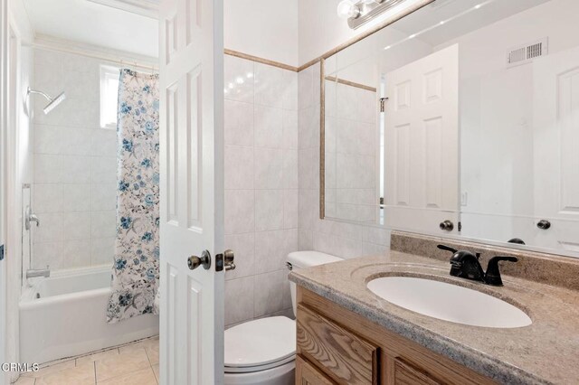 full bathroom featuring toilet, vanity, tile walls, tile patterned flooring, and shower / bath combo with shower curtain