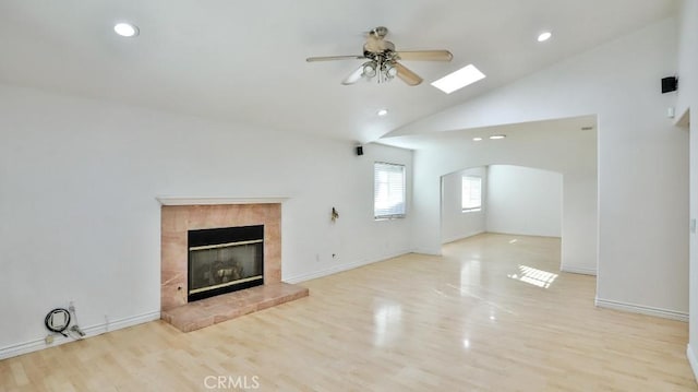 unfurnished living room with ceiling fan, light wood-type flooring, a fireplace, and high vaulted ceiling