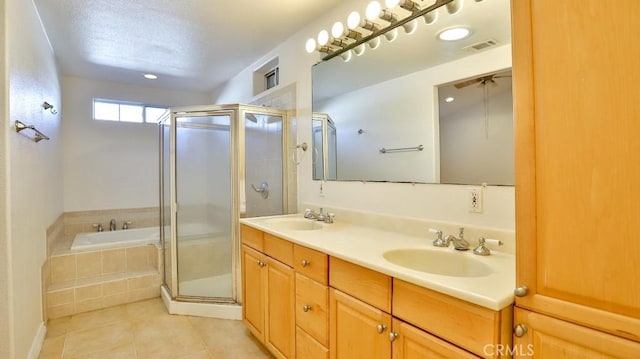 bathroom featuring plus walk in shower, tile patterned flooring, a textured ceiling, and vanity