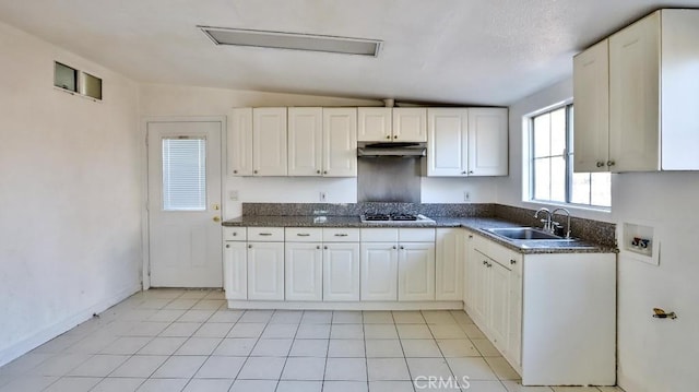 kitchen featuring sink, white cabinetry, stainless steel gas stovetop, and vaulted ceiling