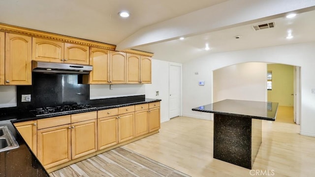 kitchen featuring black gas stovetop, lofted ceiling, light hardwood / wood-style floors, a kitchen island, and light brown cabinetry