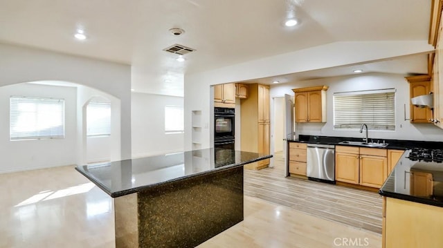 kitchen featuring vaulted ceiling, a kitchen island, stainless steel dishwasher, sink, and light hardwood / wood-style flooring