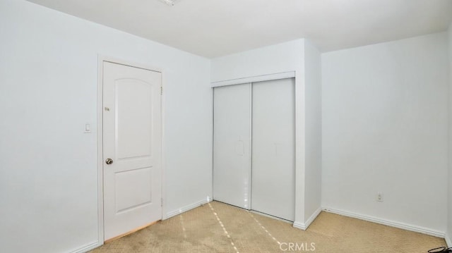 unfurnished bedroom featuring light carpet and a closet