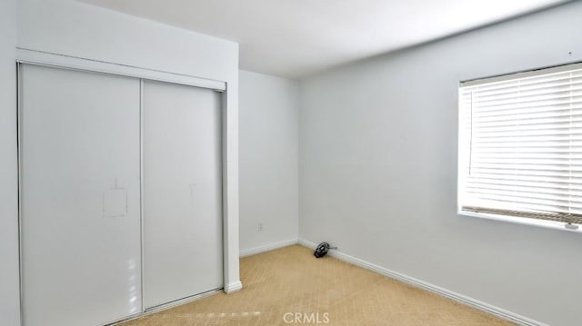 unfurnished bedroom featuring light colored carpet and a closet