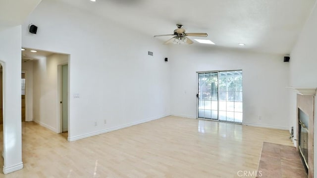 unfurnished living room featuring ceiling fan, high vaulted ceiling, a fireplace, and light hardwood / wood-style floors