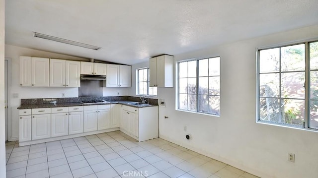 kitchen featuring stainless steel gas stovetop, a wealth of natural light, white cabinetry, and sink