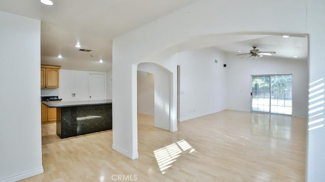 unfurnished living room with vaulted ceiling, ceiling fan, and light hardwood / wood-style flooring