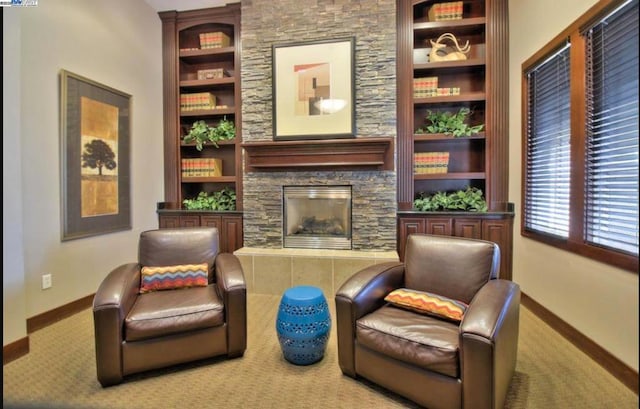 living area featuring light colored carpet, built in shelves, and a stone fireplace