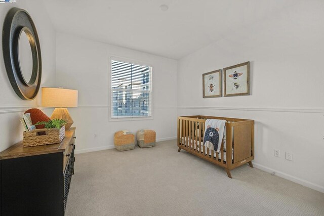 bedroom featuring light colored carpet and a nursery area