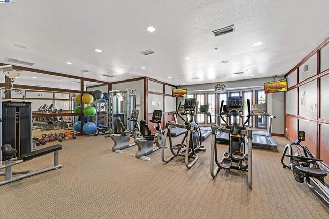 gym with light colored carpet and a textured ceiling