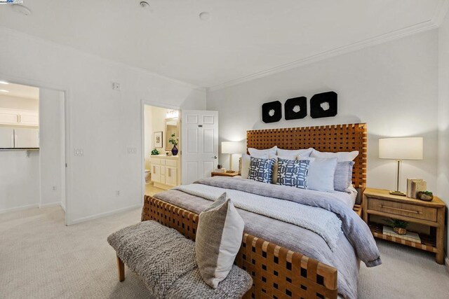 carpeted bedroom featuring crown molding and ensuite bath