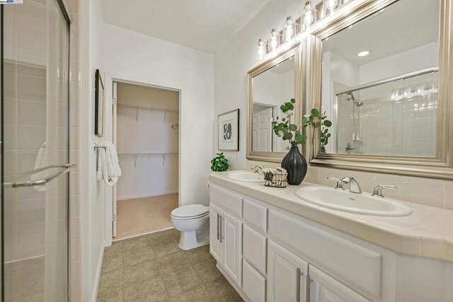 bathroom featuring a shower with shower door, toilet, and vanity