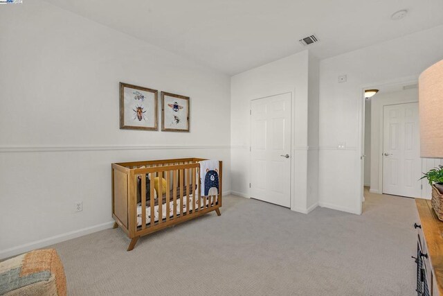 bedroom with light carpet and a nursery area