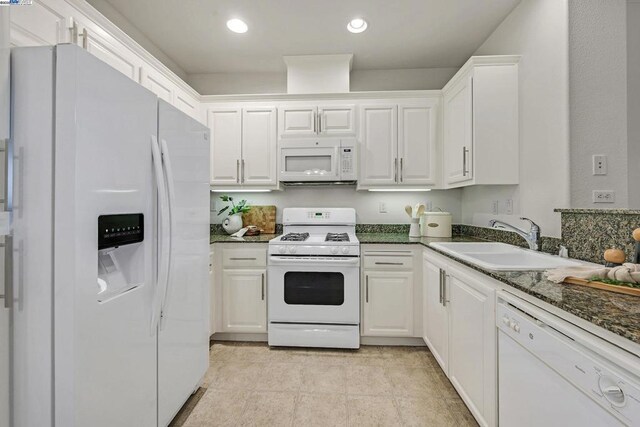 kitchen with sink, dark stone countertops, white cabinets, and white appliances