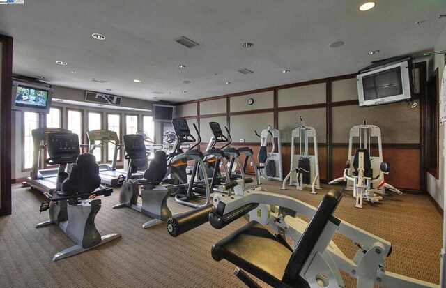 exercise room with carpet and wooden walls