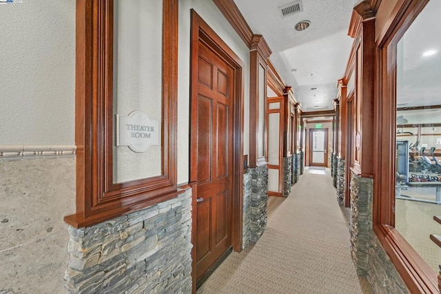 corridor featuring light carpet, crown molding, and a textured ceiling