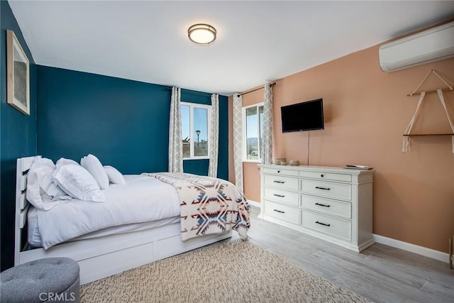 bedroom featuring light hardwood / wood-style floors and a wall unit AC