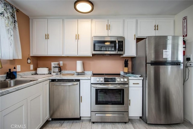 kitchen featuring light wood-type flooring, appliances with stainless steel finishes, and white cabinets