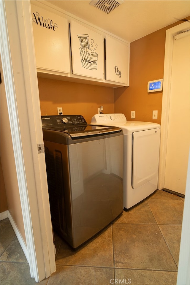 clothes washing area with cabinets and washer and clothes dryer