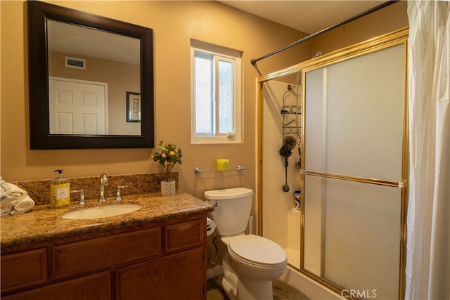 bathroom with toilet, a shower with shower door, and vanity