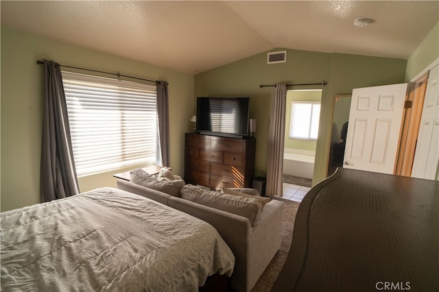 bedroom with ensuite bath, a textured ceiling, and vaulted ceiling