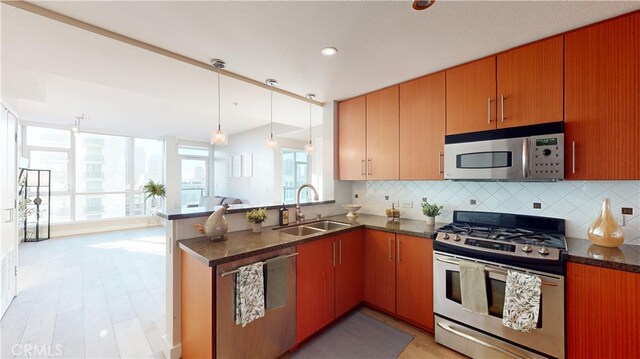 kitchen with backsplash, kitchen peninsula, appliances with stainless steel finishes, and sink