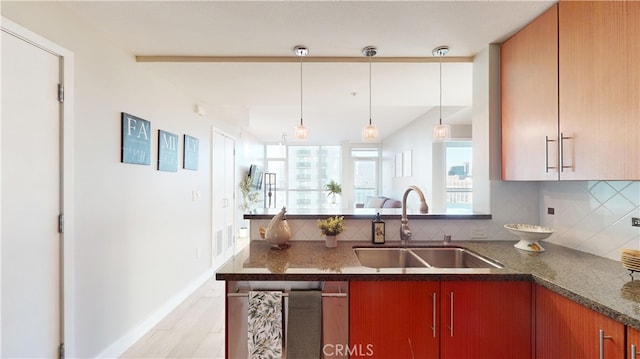 kitchen with light hardwood / wood-style floors, backsplash, hanging light fixtures, and sink