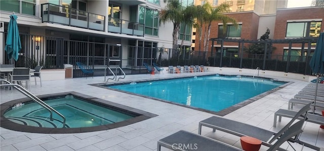 view of swimming pool featuring a hot tub and a patio area