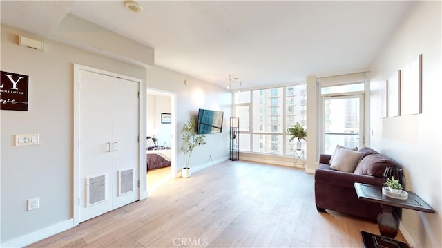 interior space with a wall of windows and light hardwood / wood-style floors