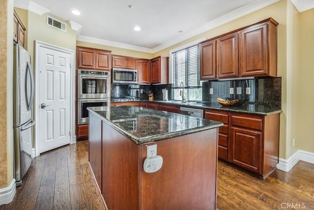 kitchen with tasteful backsplash, dark stone countertops, a kitchen island, appliances with stainless steel finishes, and dark hardwood / wood-style flooring