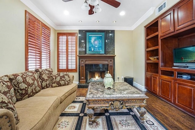 living room with ceiling fan, a high end fireplace, ornamental molding, and wood-type flooring