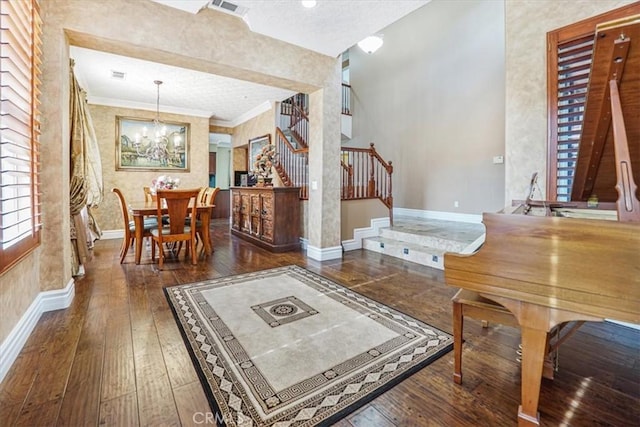 living room with a textured ceiling, ornamental molding, dark hardwood / wood-style floors, and a notable chandelier