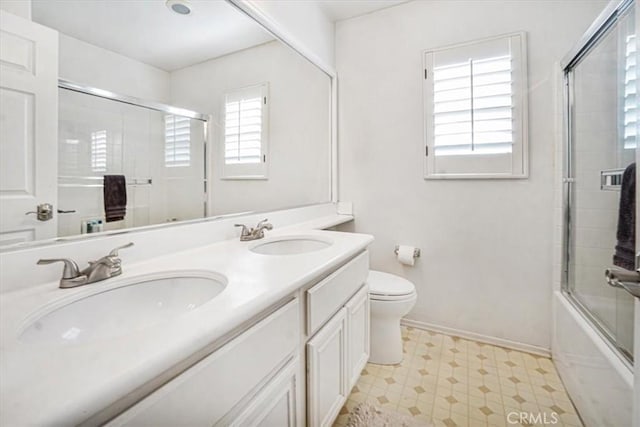 full bathroom featuring plenty of natural light, bath / shower combo with glass door, toilet, and vanity