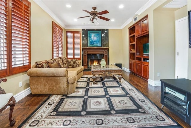 living room featuring ceiling fan, dark hardwood / wood-style flooring, crown molding, and a fireplace