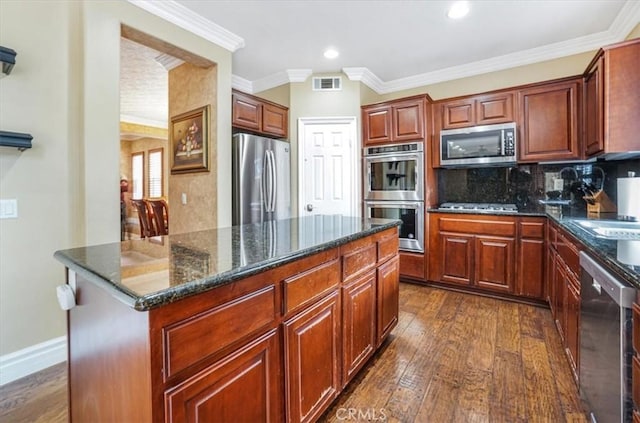 kitchen featuring dark wood-type flooring, stainless steel appliances, crown molding, and a kitchen island