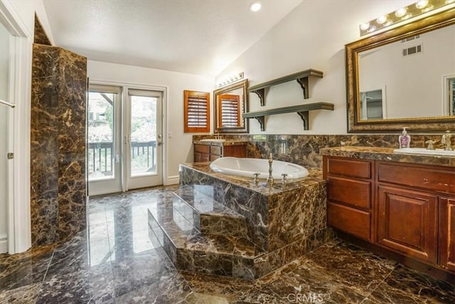 bathroom featuring a relaxing tiled tub, vanity, and lofted ceiling