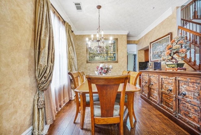 dining area featuring dark wood-type flooring, a textured ceiling, crown molding, and an inviting chandelier