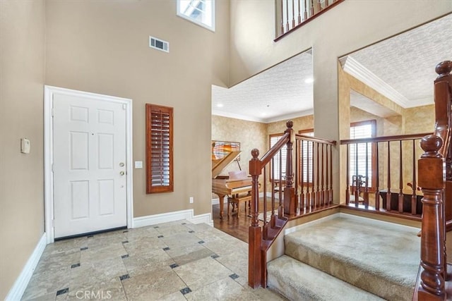 foyer entrance with a textured ceiling, ornamental molding, and a healthy amount of sunlight