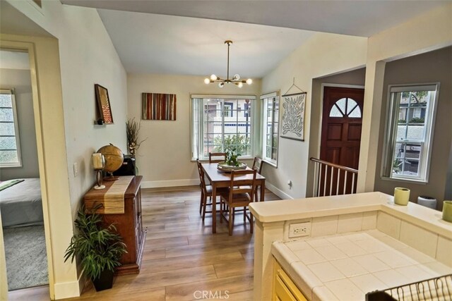 interior space featuring vaulted ceiling, an inviting chandelier, and hardwood / wood-style floors