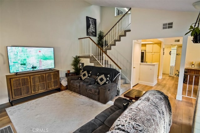 living room with high vaulted ceiling and light hardwood / wood-style floors