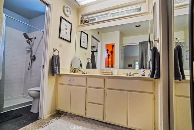 bathroom featuring toilet, vanity, and a tile shower