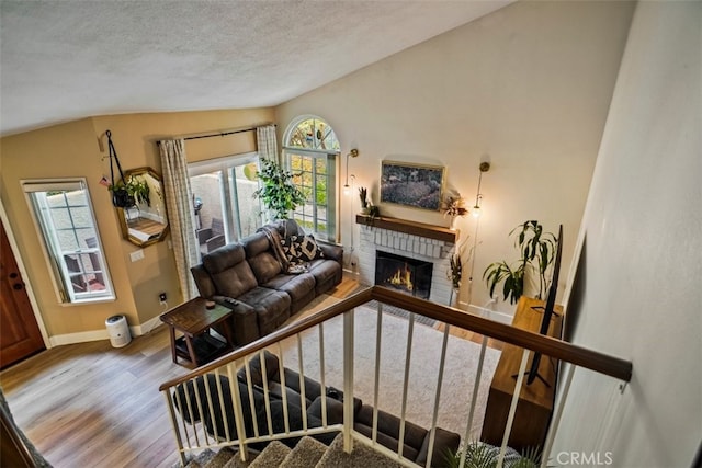 living room with vaulted ceiling, a fireplace, a wealth of natural light, and hardwood / wood-style floors