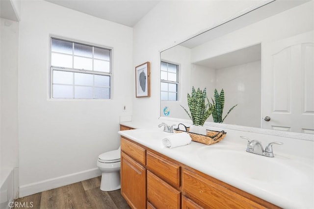 bathroom featuring hardwood / wood-style floors, toilet, vanity, and a tub to relax in