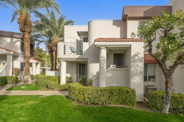 view of front of home featuring a balcony, a front lawn, and central AC unit