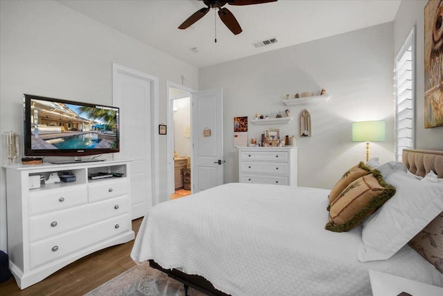 bedroom with ceiling fan, dark wood-type flooring, and connected bathroom