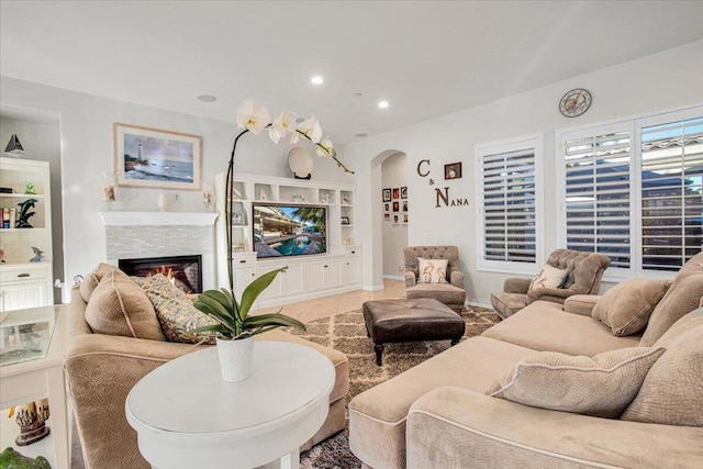 living room with a stone fireplace and light tile patterned flooring