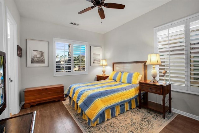 bedroom with ceiling fan, multiple windows, and dark hardwood / wood-style floors