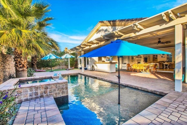 view of swimming pool featuring ceiling fan, an outdoor kitchen, a patio, and an in ground hot tub