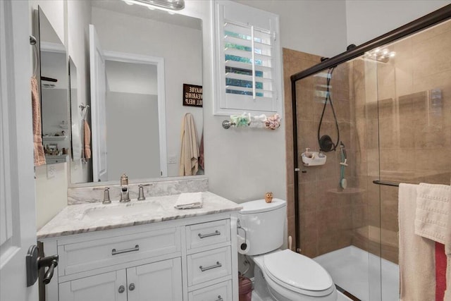 bathroom with toilet, a shower with door, and vanity