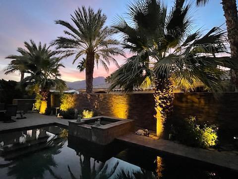 pool at dusk featuring a hot tub, a water view, and a patio